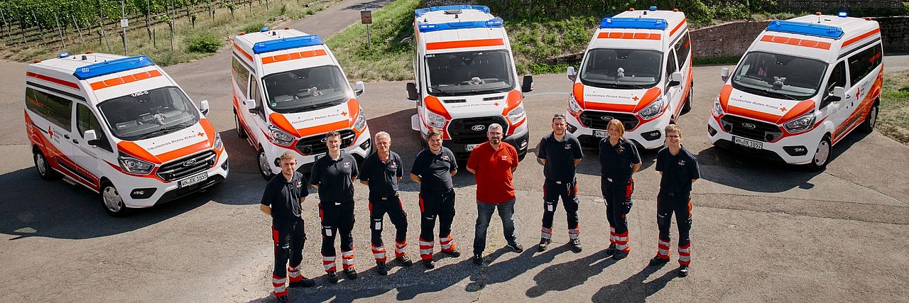 Mitglieder des DRK-Krankentransports vor ihren Fahrzeugen